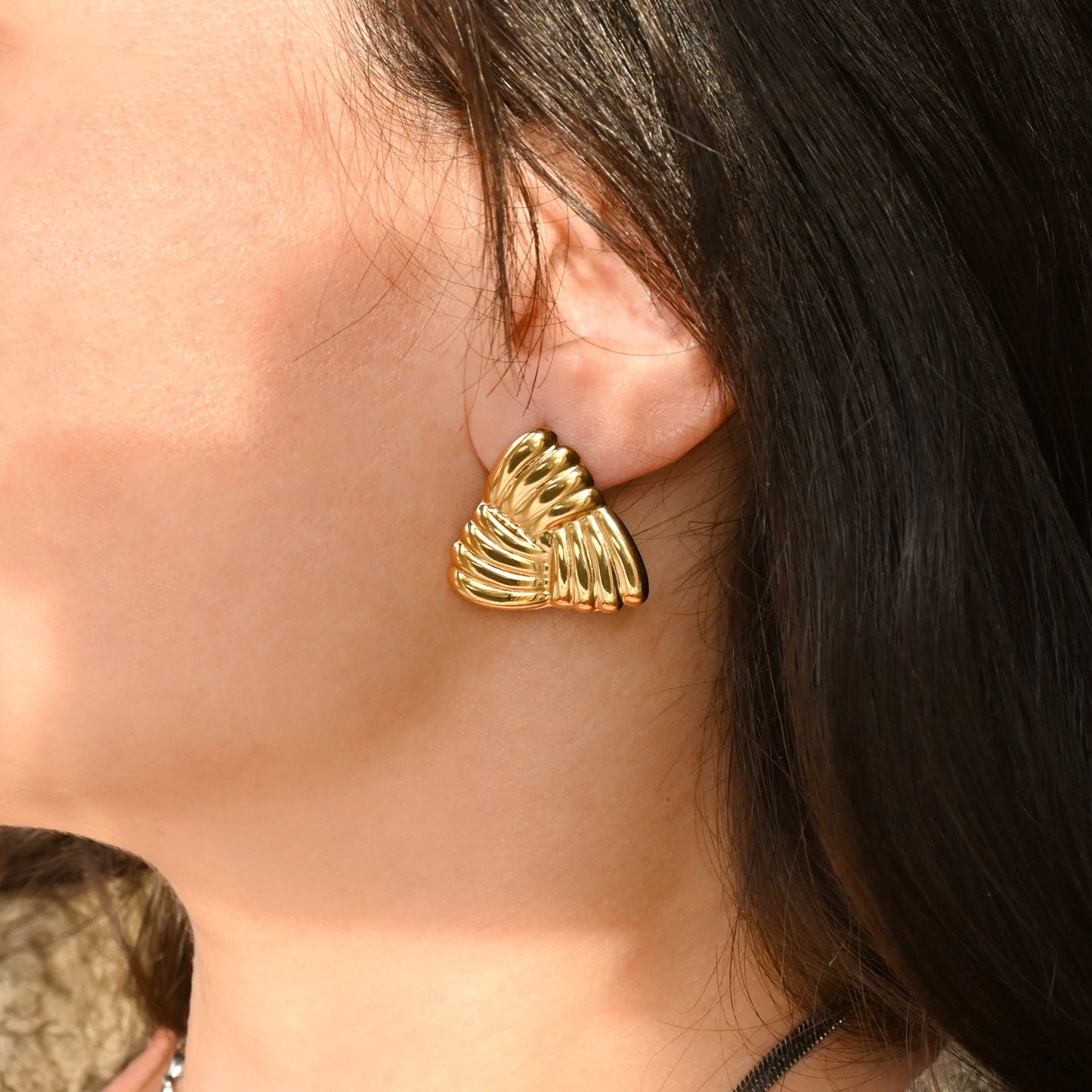 Gold braided triangle earrings worn by a person with dark hair.