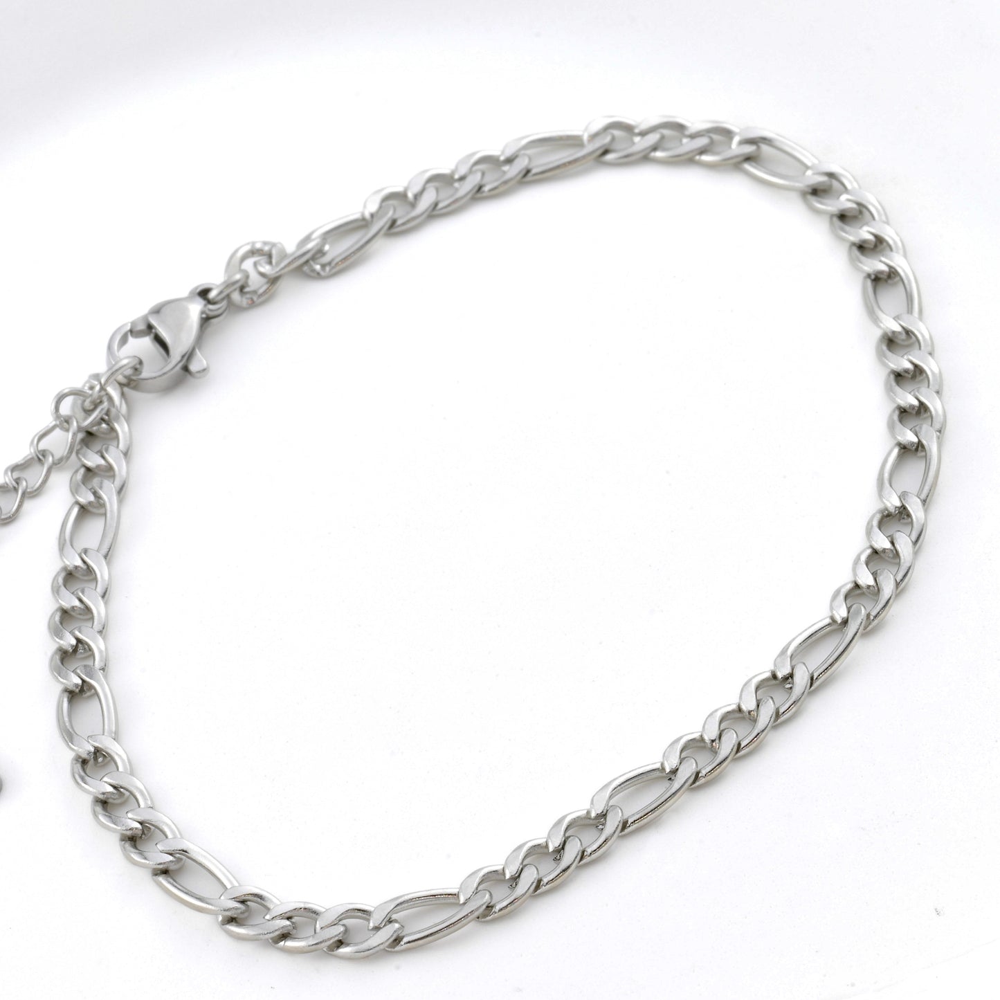 Silver figaro chain bracelet with a lobster claw claspmon a white background