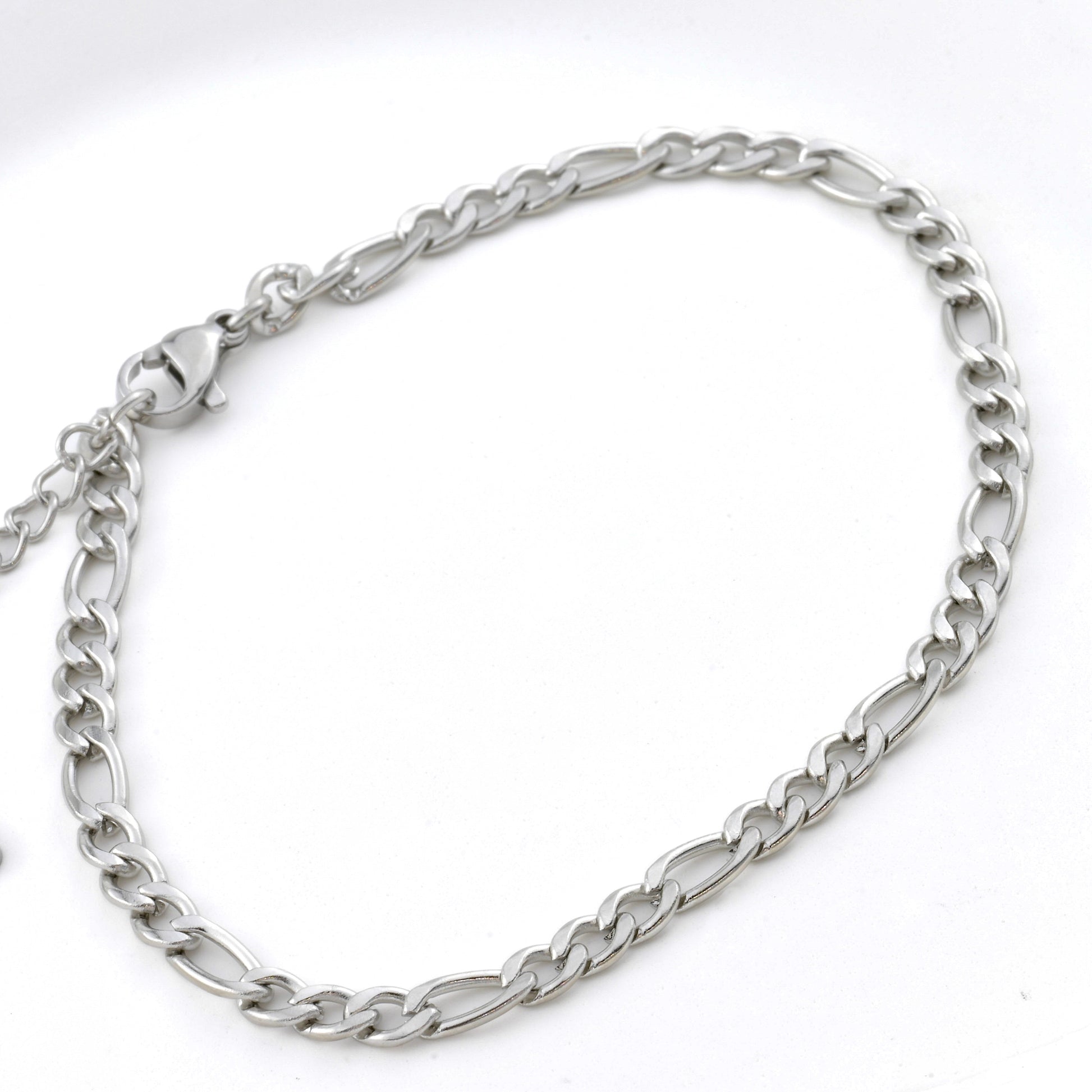 Silver figaro chain bracelet with a lobster claw claspmon a white background