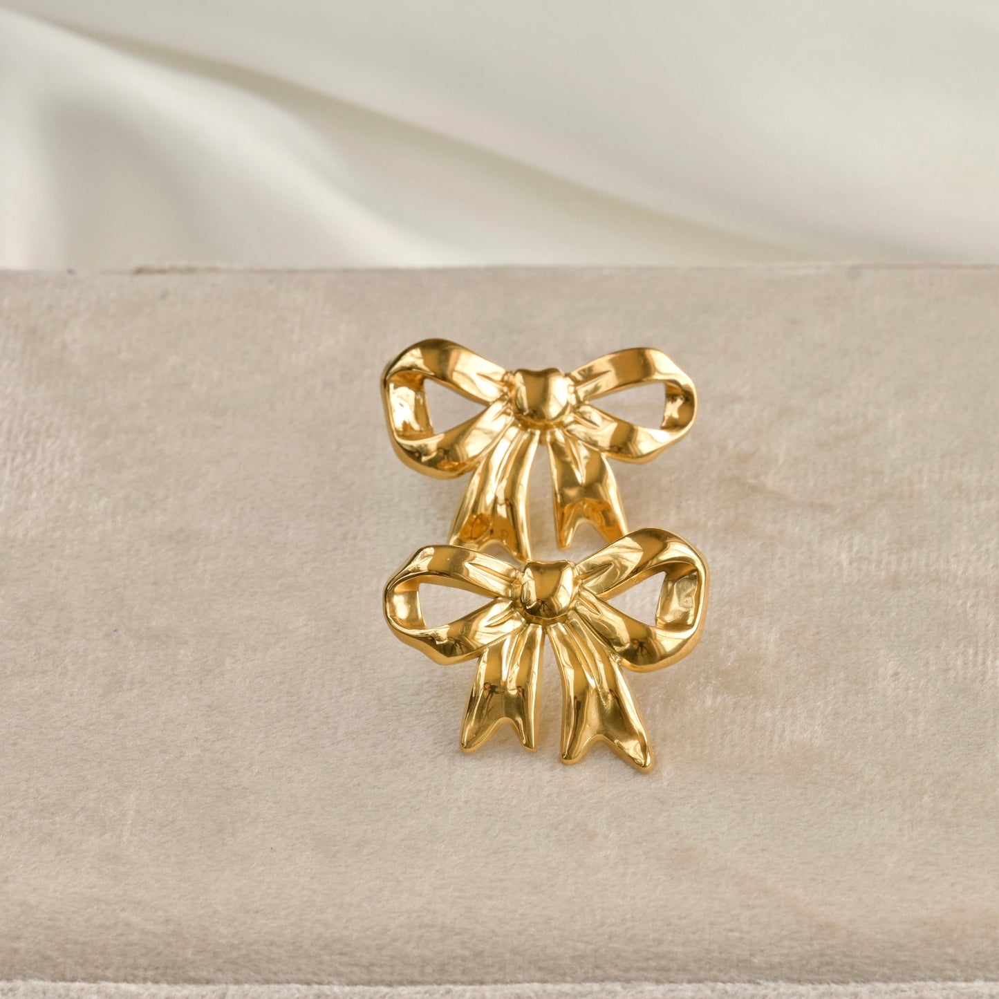 front view of both earrings on a beige fabric background