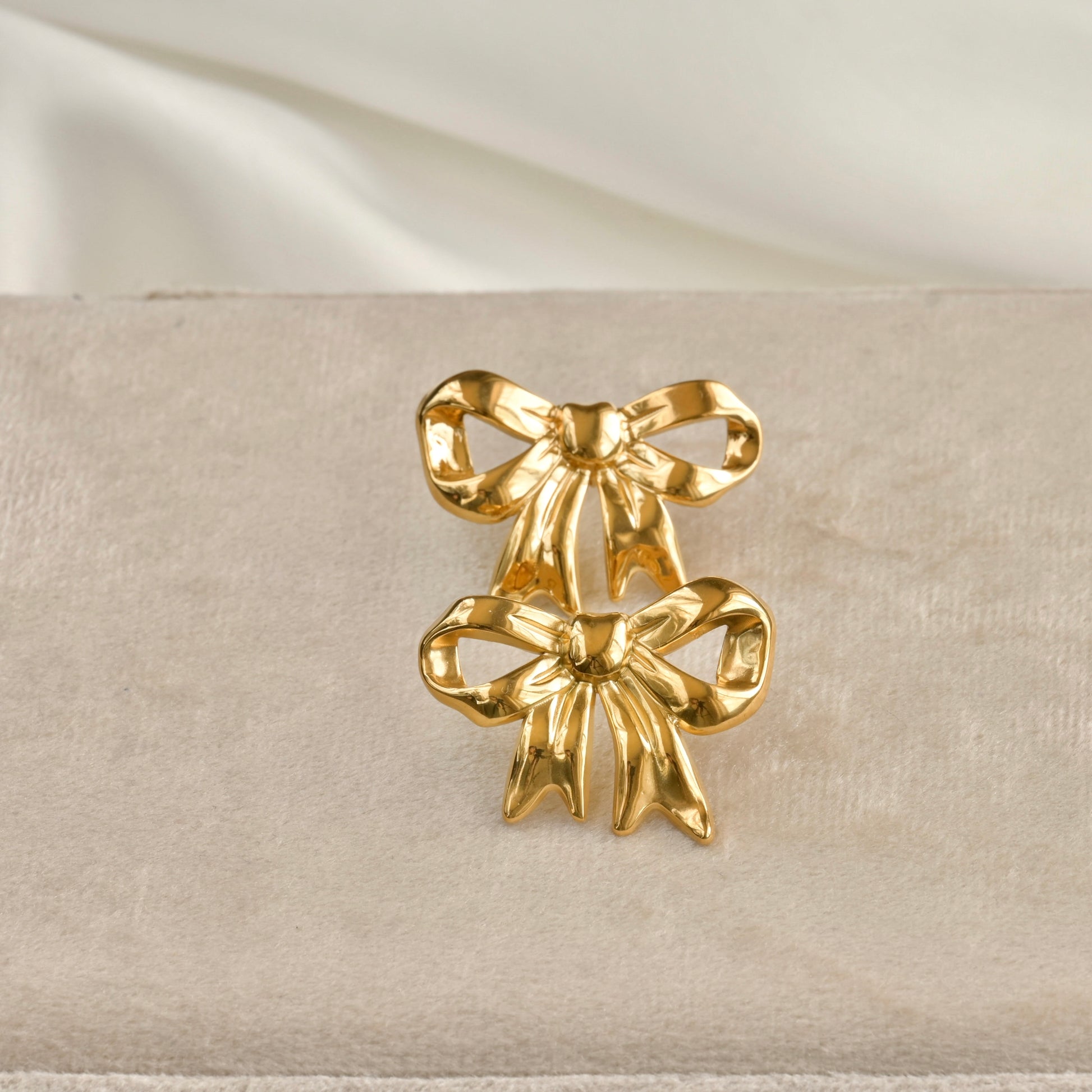 front view of both earrings on a beige fabric background