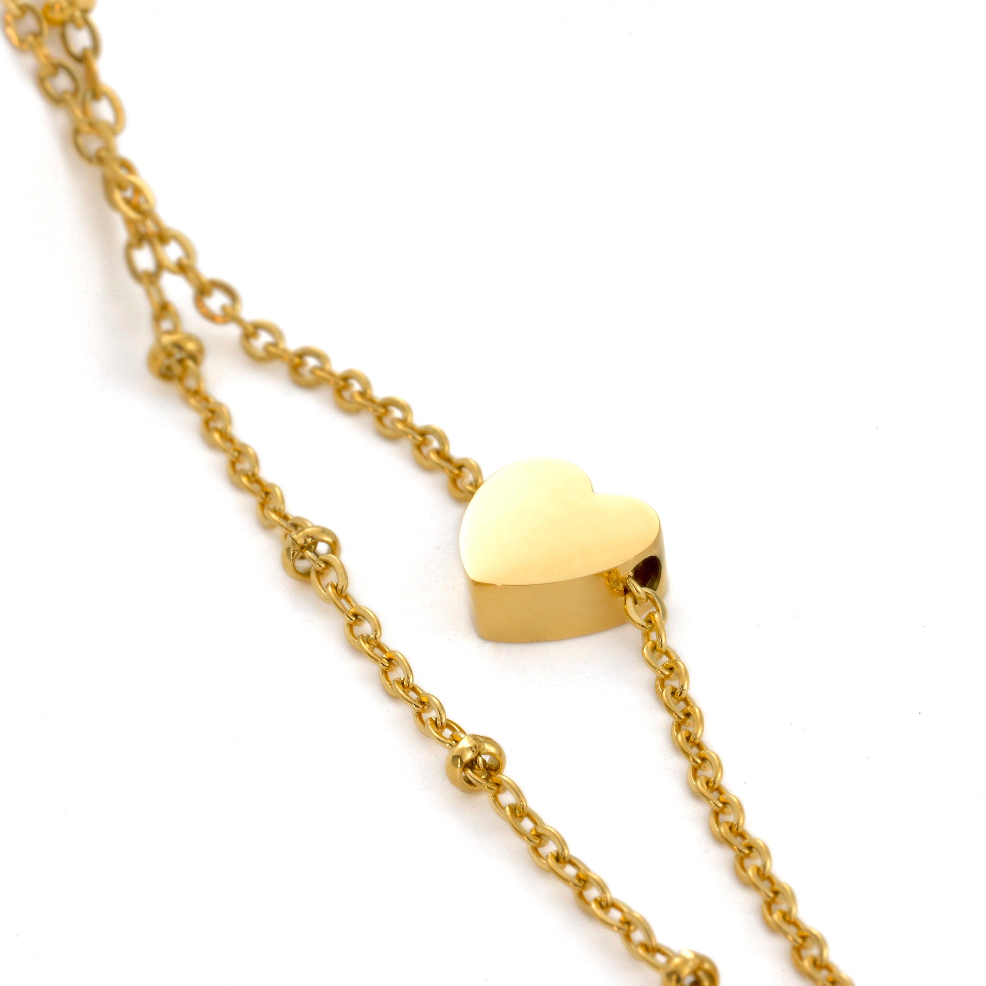 Gold heart charm anklet on a gold cable chain paired with a beaded satellite chain against a white background