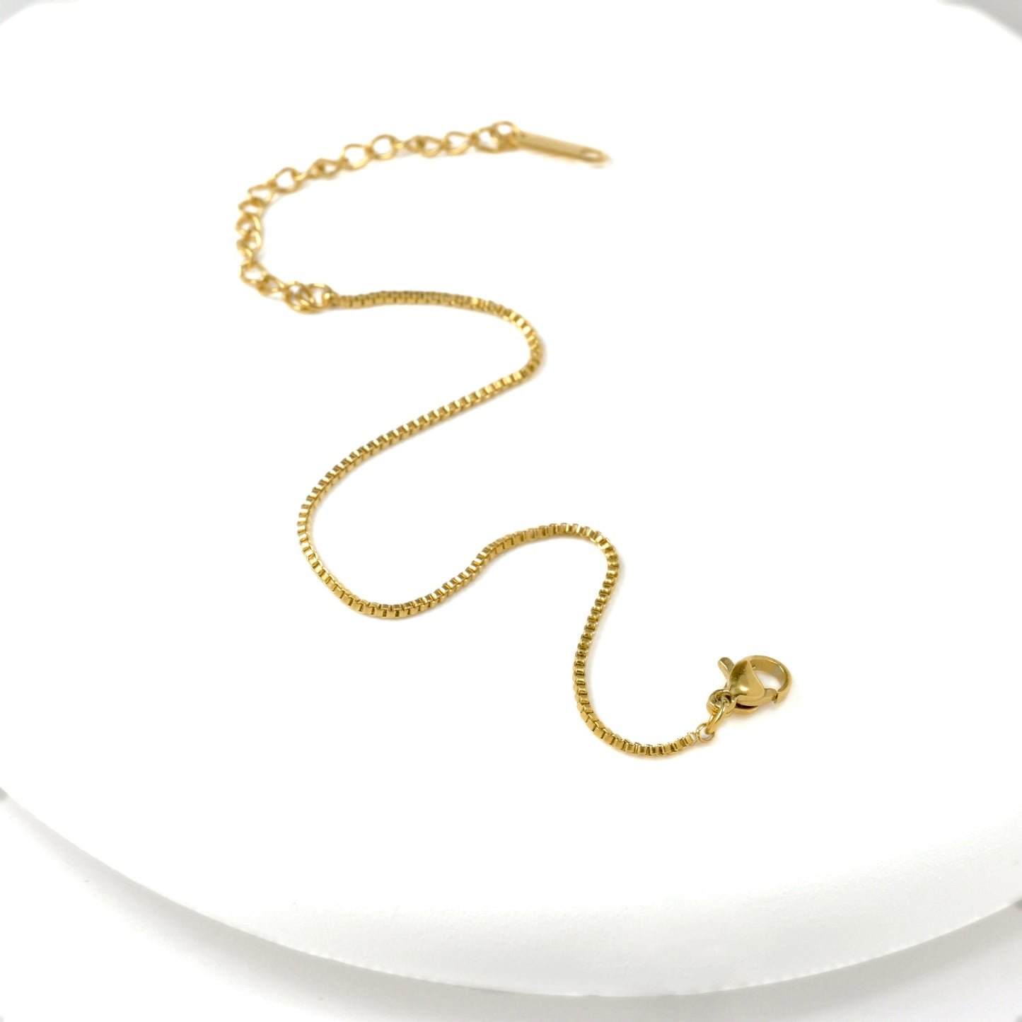 Gold box chain bracelet with an extender on a white background