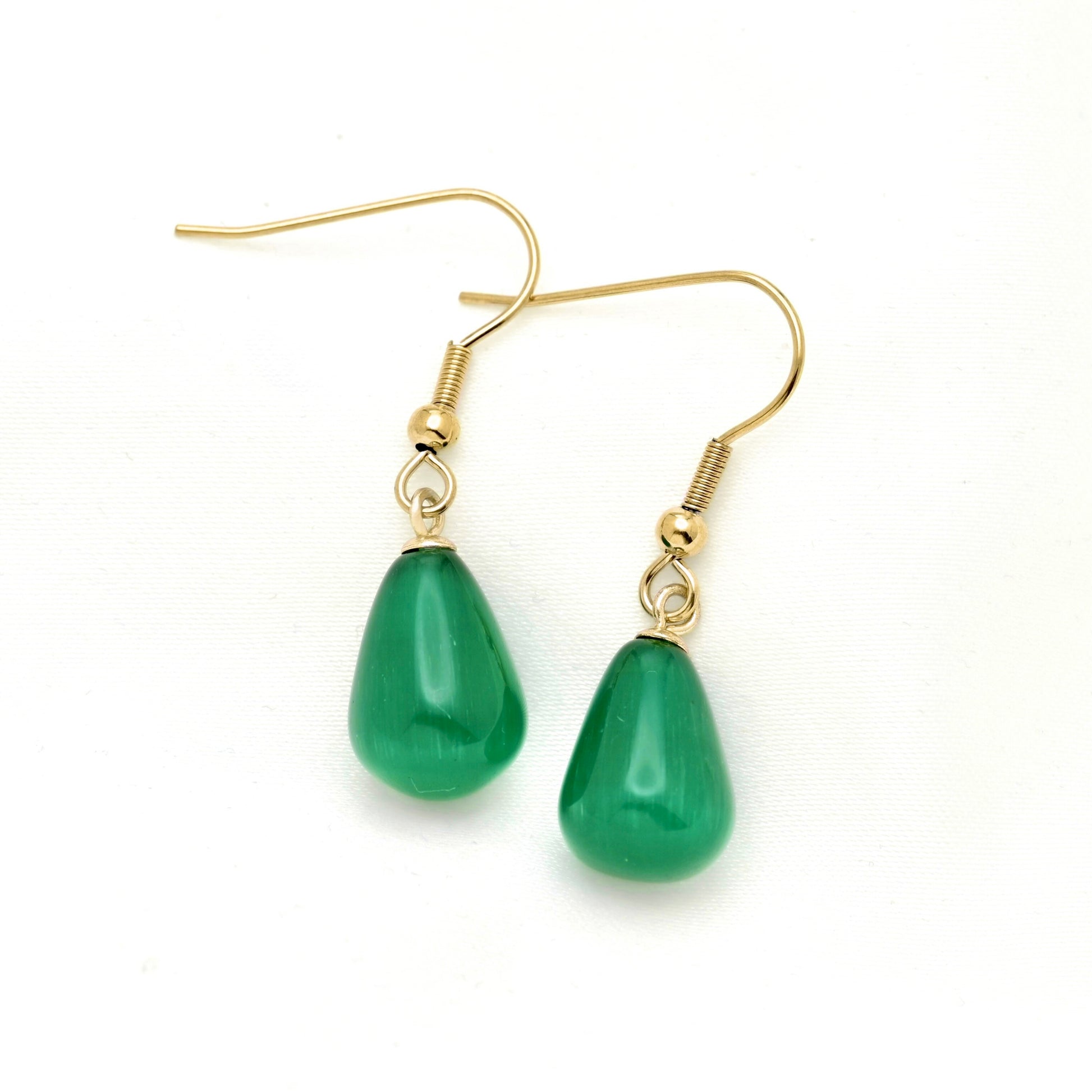 A pair of gold-tone fishhook drop earrings with smooth, teardrop-shaped emerald green stone pendants, shown on a plain white background.