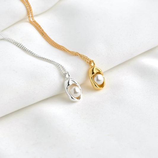 Two  sterling silver pearl necklaces, one gold and one silver, on a white surface.