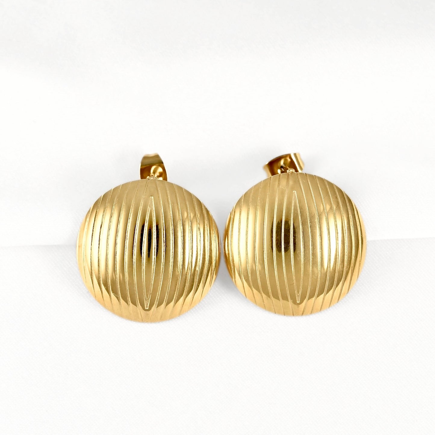 A pair of vintage gold-tone round clip-on earrings with a vertically ribbed textured surface, displayed on a clean white background.