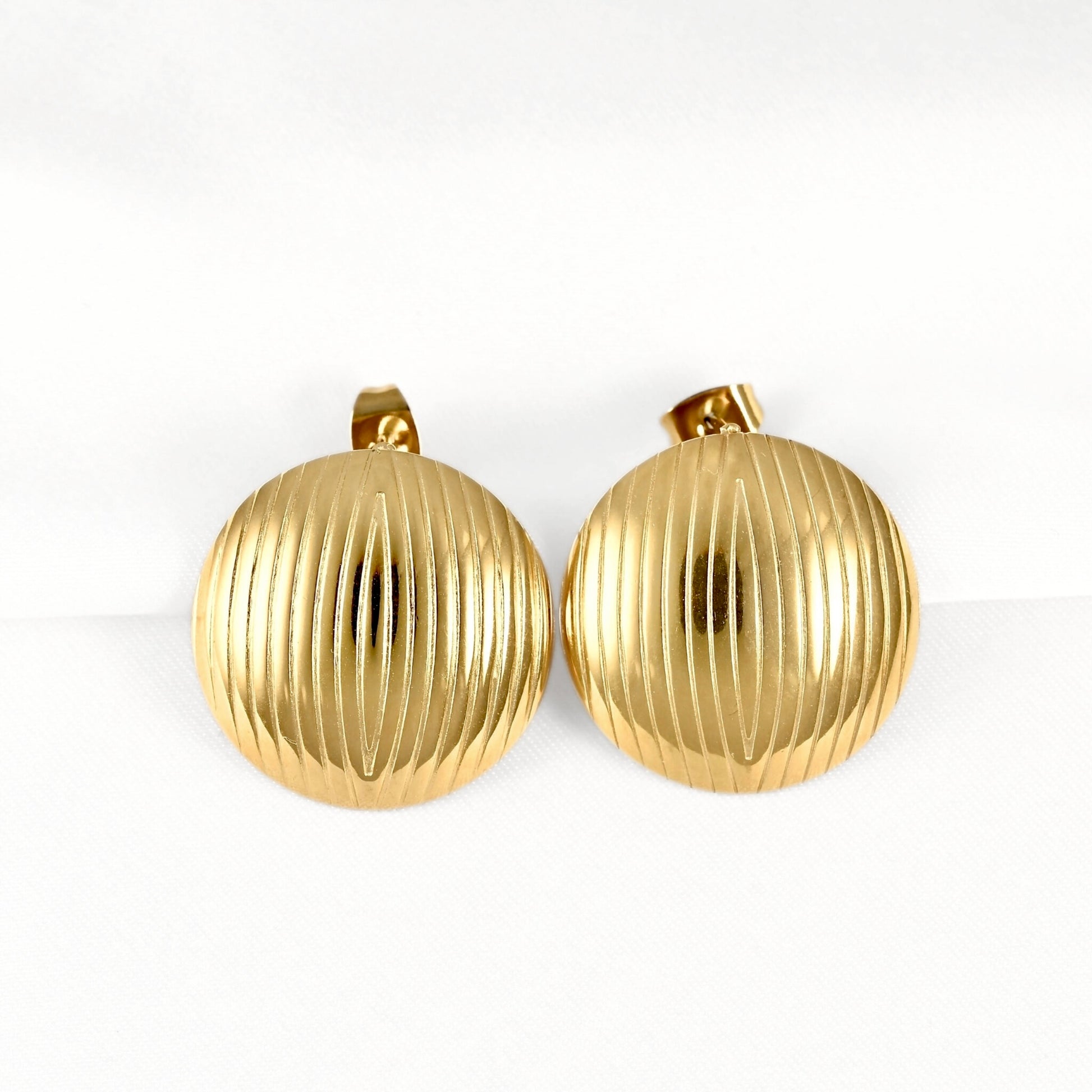 A pair of vintage gold-tone round clip-on earrings with a vertically ribbed textured surface, displayed on a clean white background.