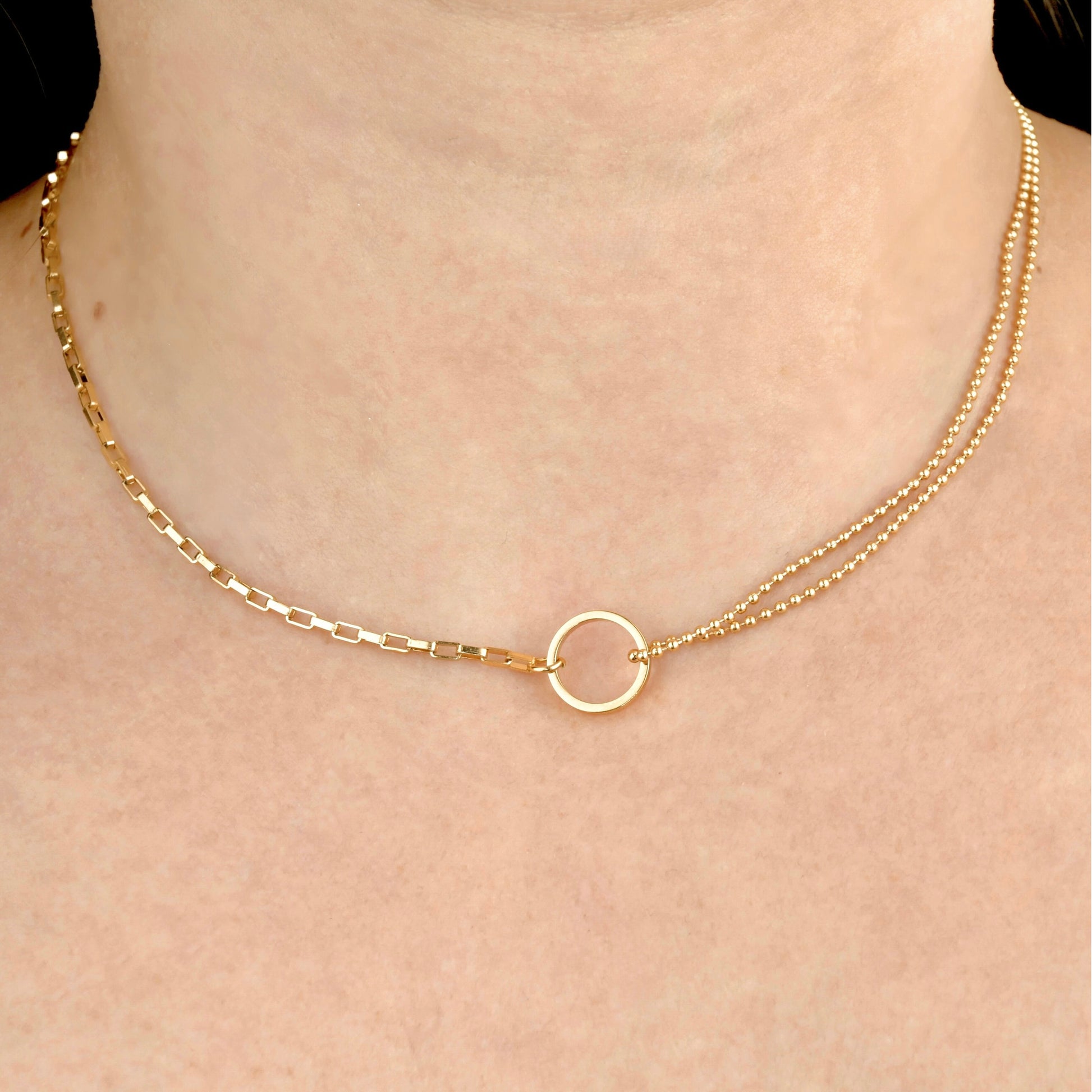 Gold circle link necklace with a bold rectangular chain and double layered ball chain on each side on a person's neck