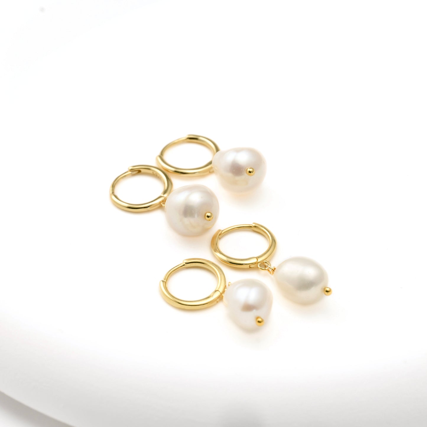 Two pairs of gold Pearl  earrings on a white background