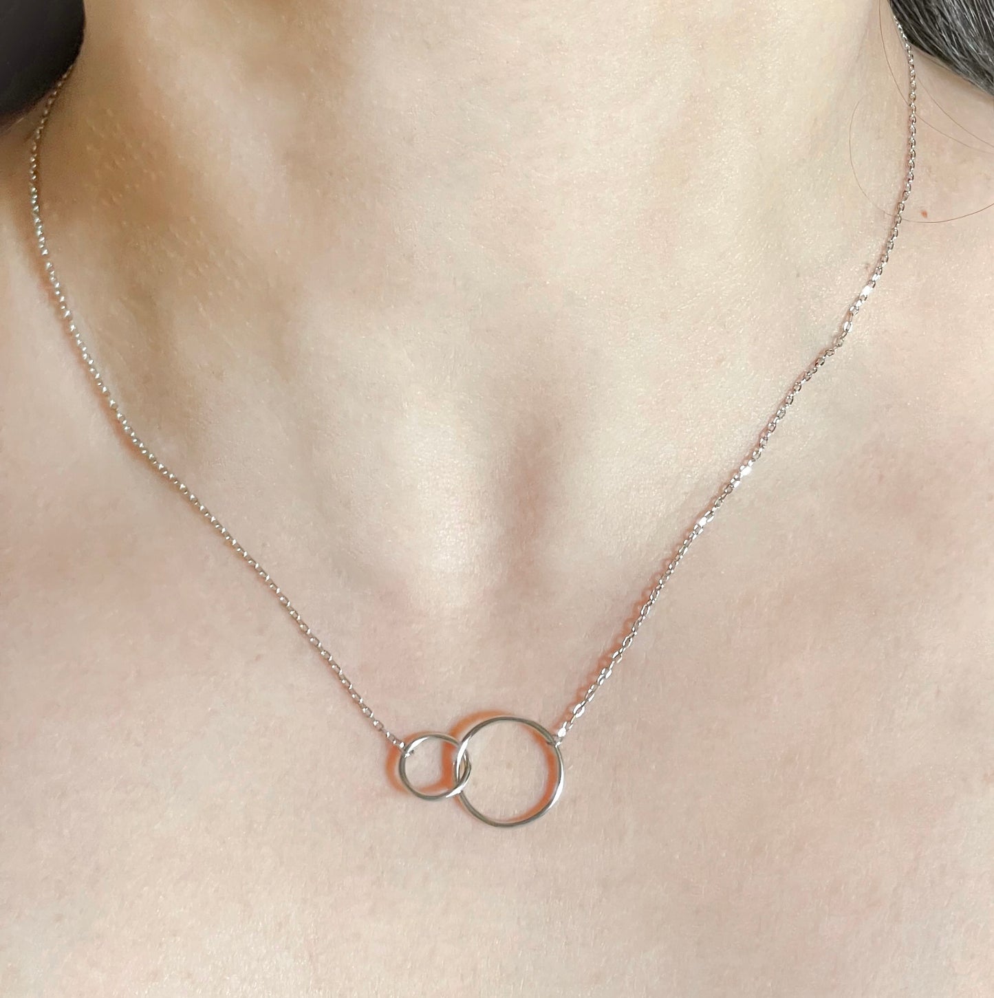 Sterling silver necklace with interlocking rings on a person's neck
