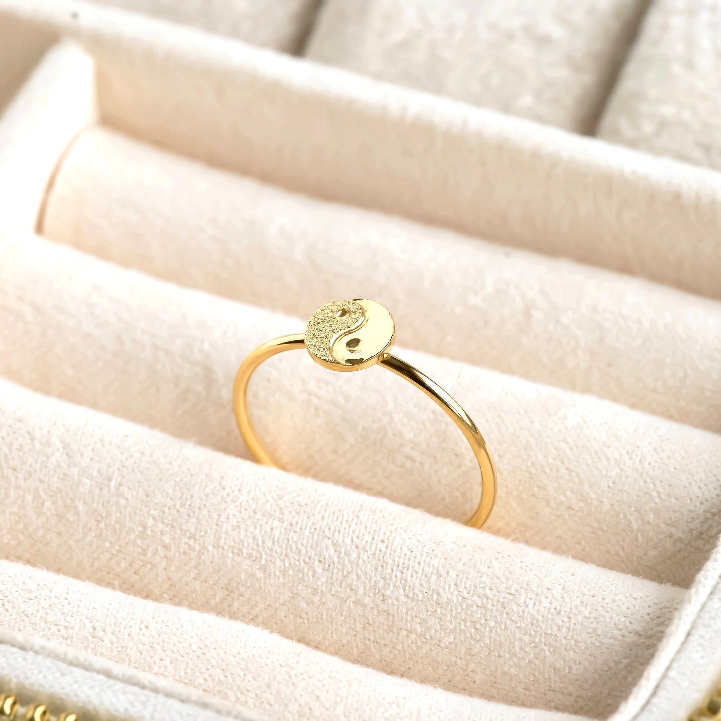 Gold ring with a round design on a beige jewelry box
