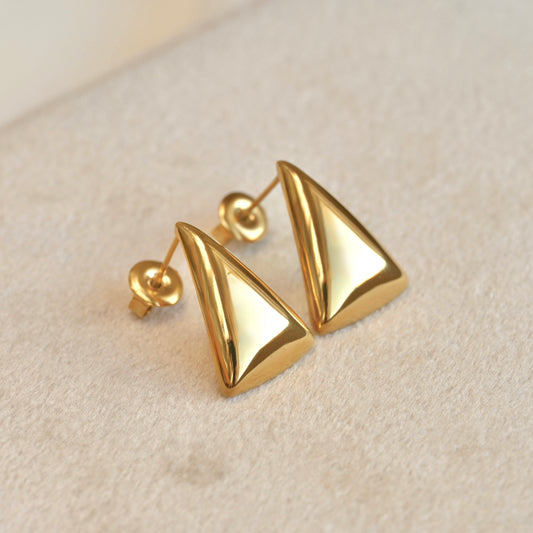 Gold triangle-shaped earrings on a beige background