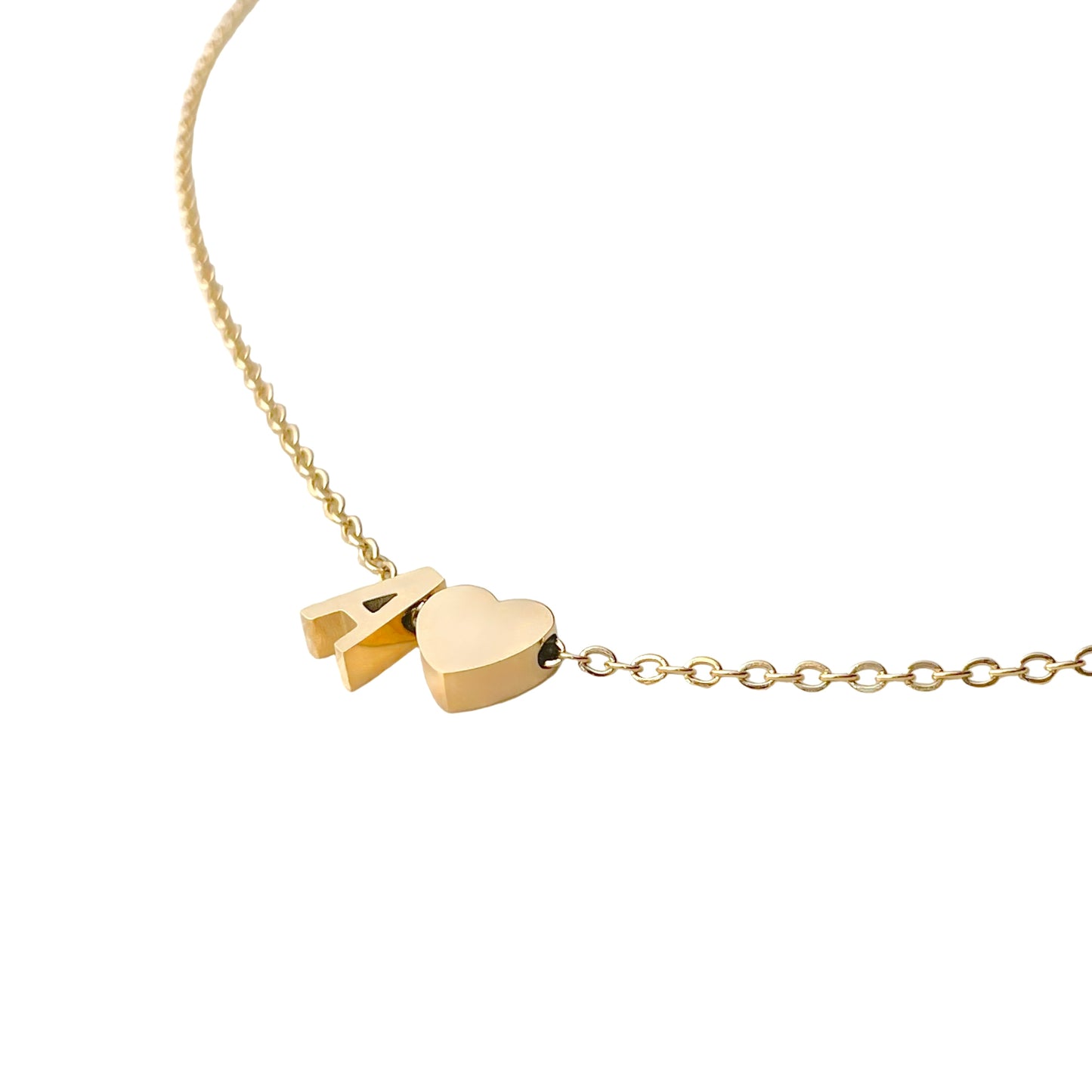 Gold necklace with a heart pendant and 'A' charm on a white background