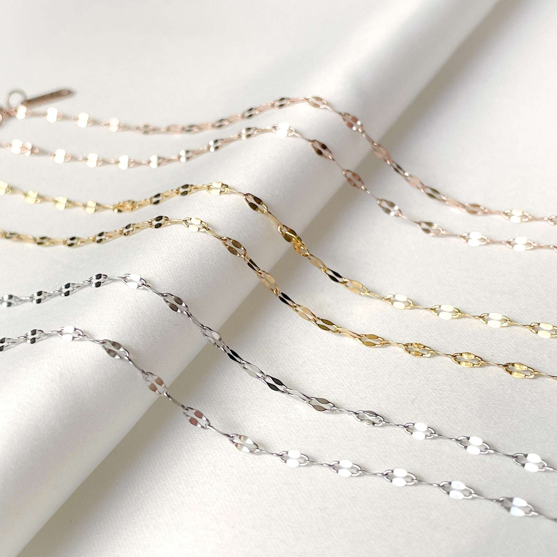 Gold , silver and rose gold sequin chain necklaces on a white background