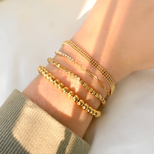  Beaded Gold bracelets in 4 different designs on a wrist with a neutral background