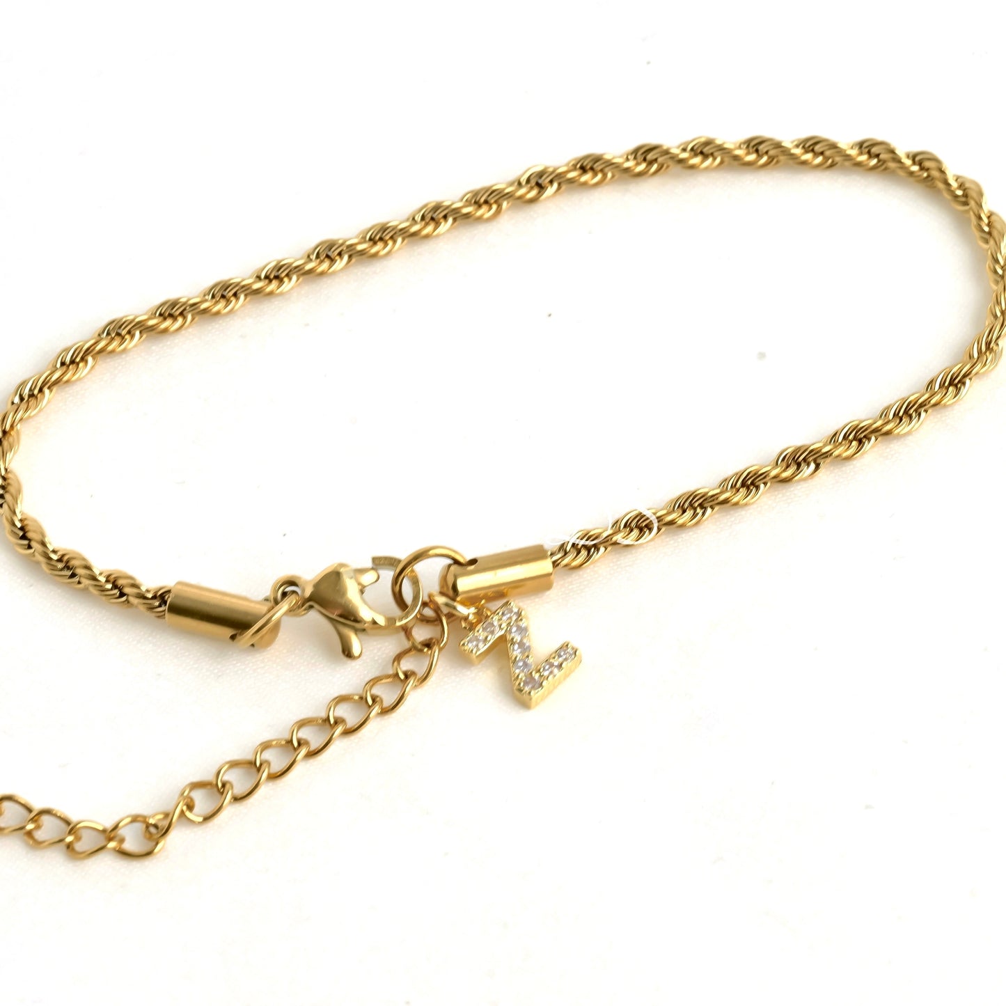 Gold chain bracelet with an initial charm at the clasp area, displayed on a white background
