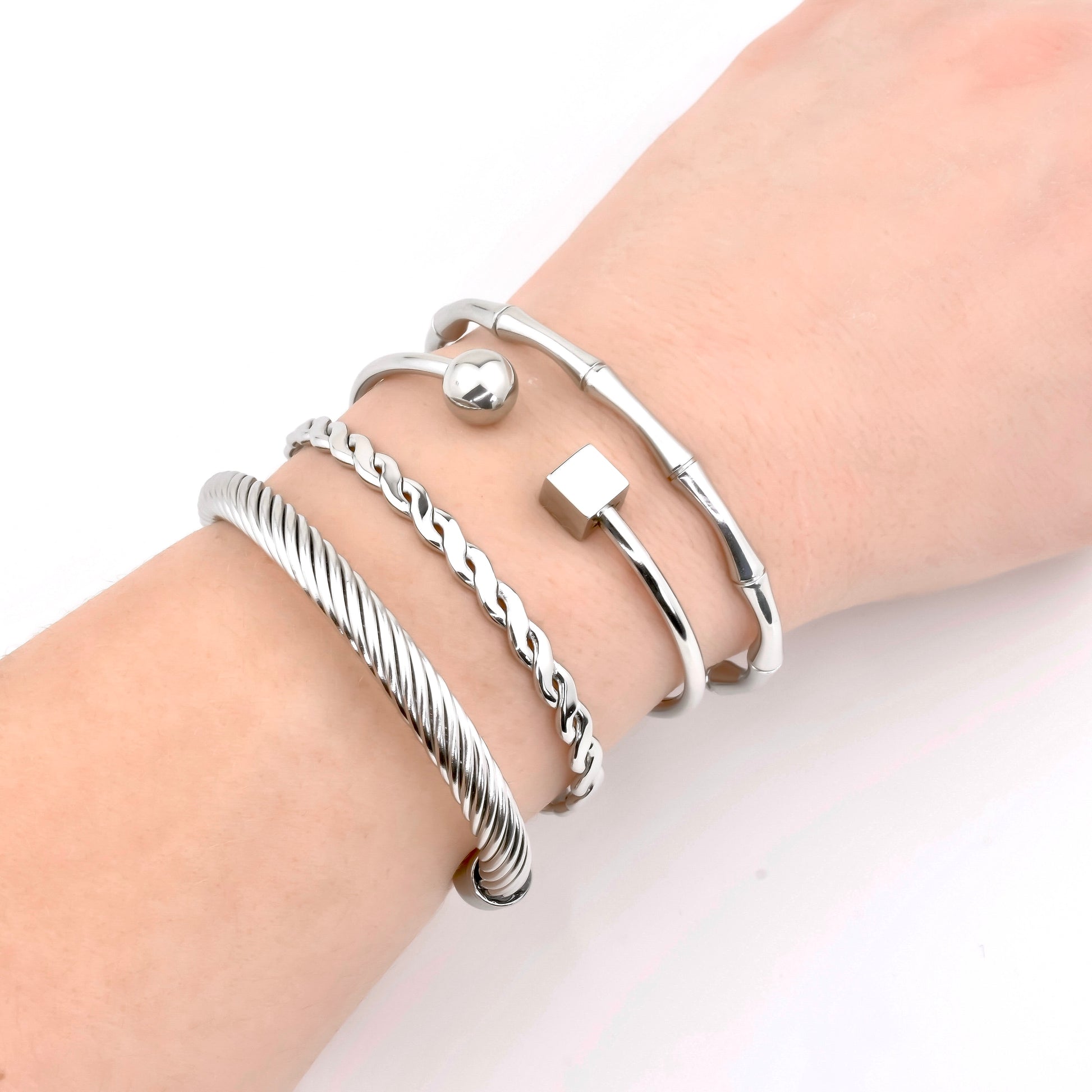 Silver cuff bracelets on a wrist against a white background