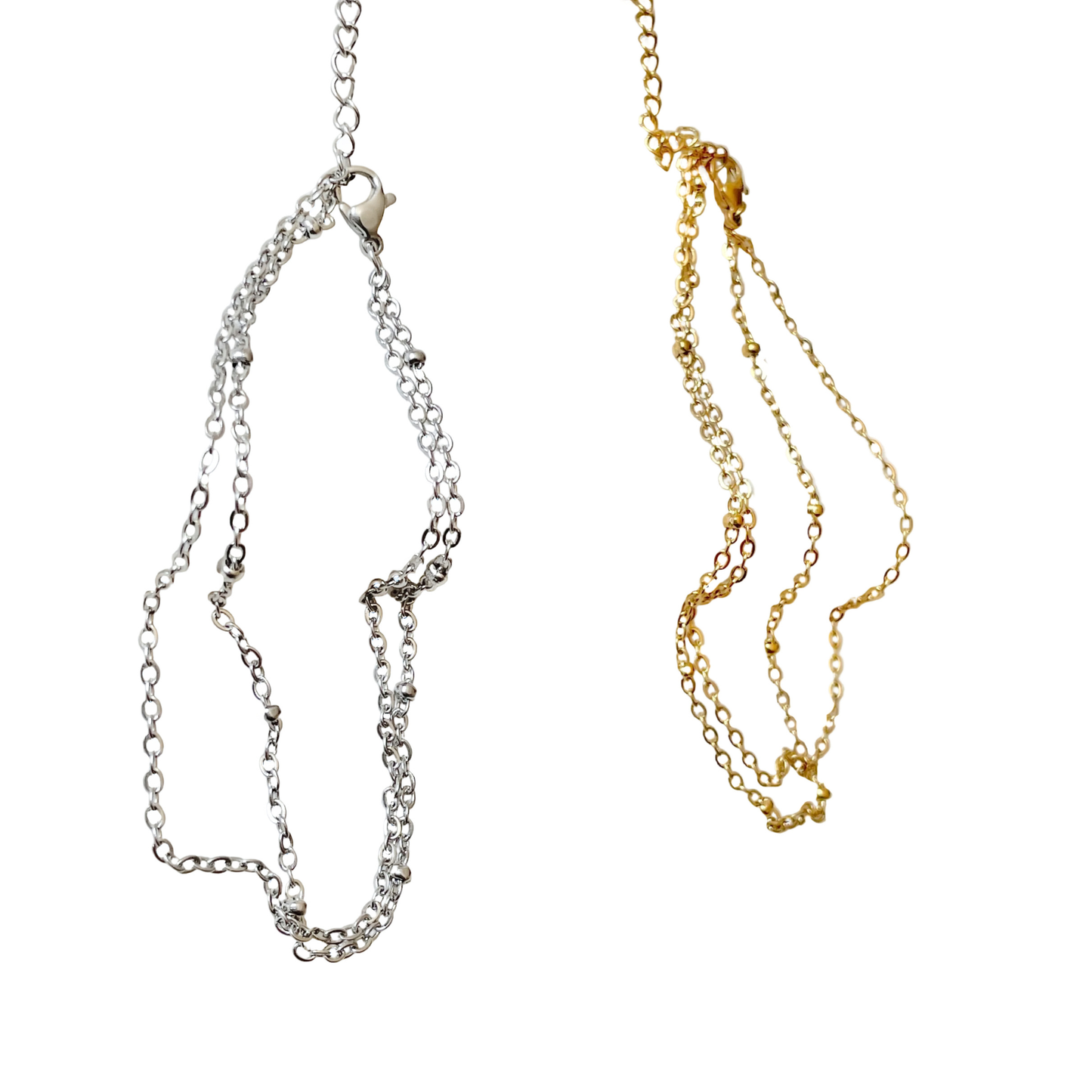 Two gold and silver chain anklets on a white background