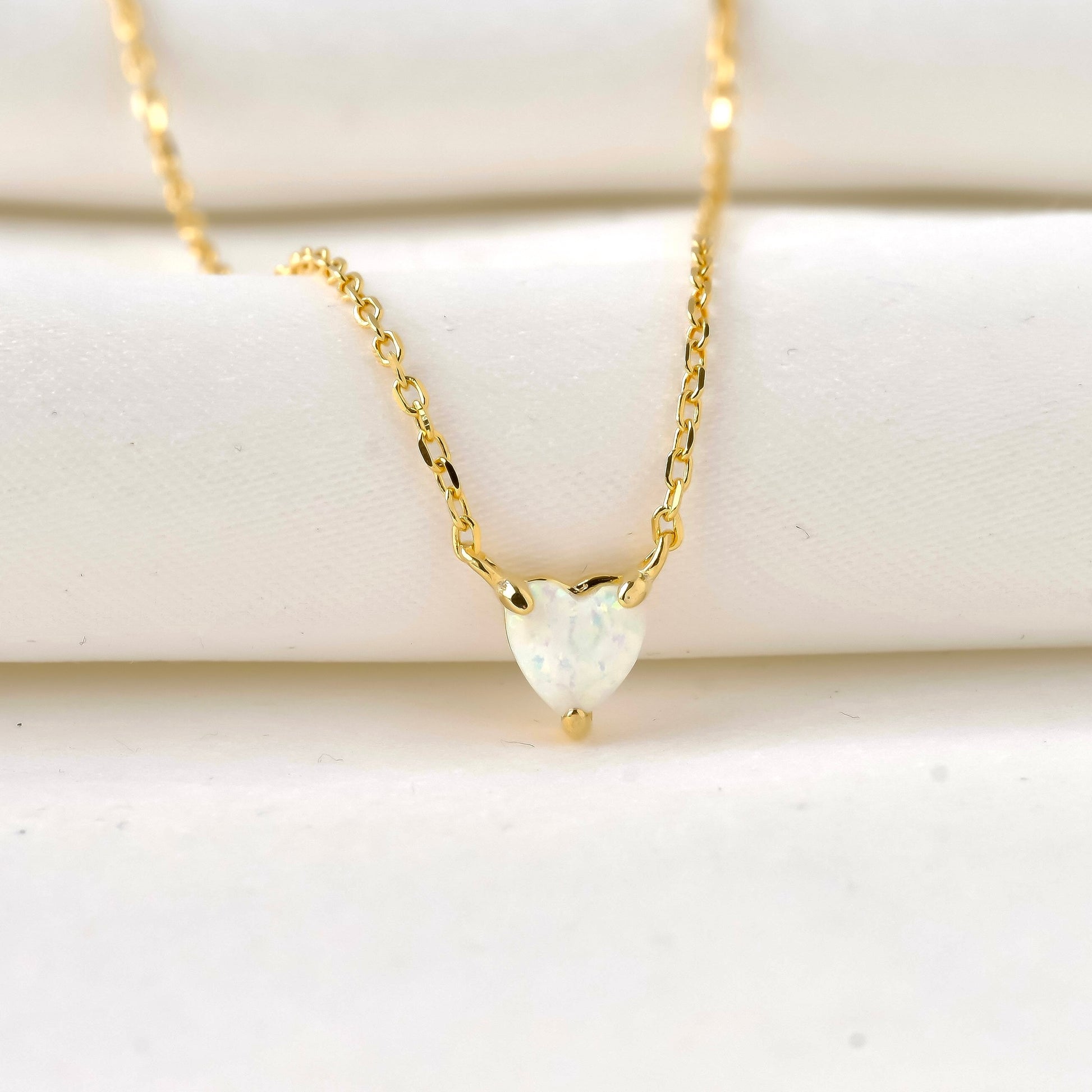 Gold necklace with a heart-shaped pendant on a white background