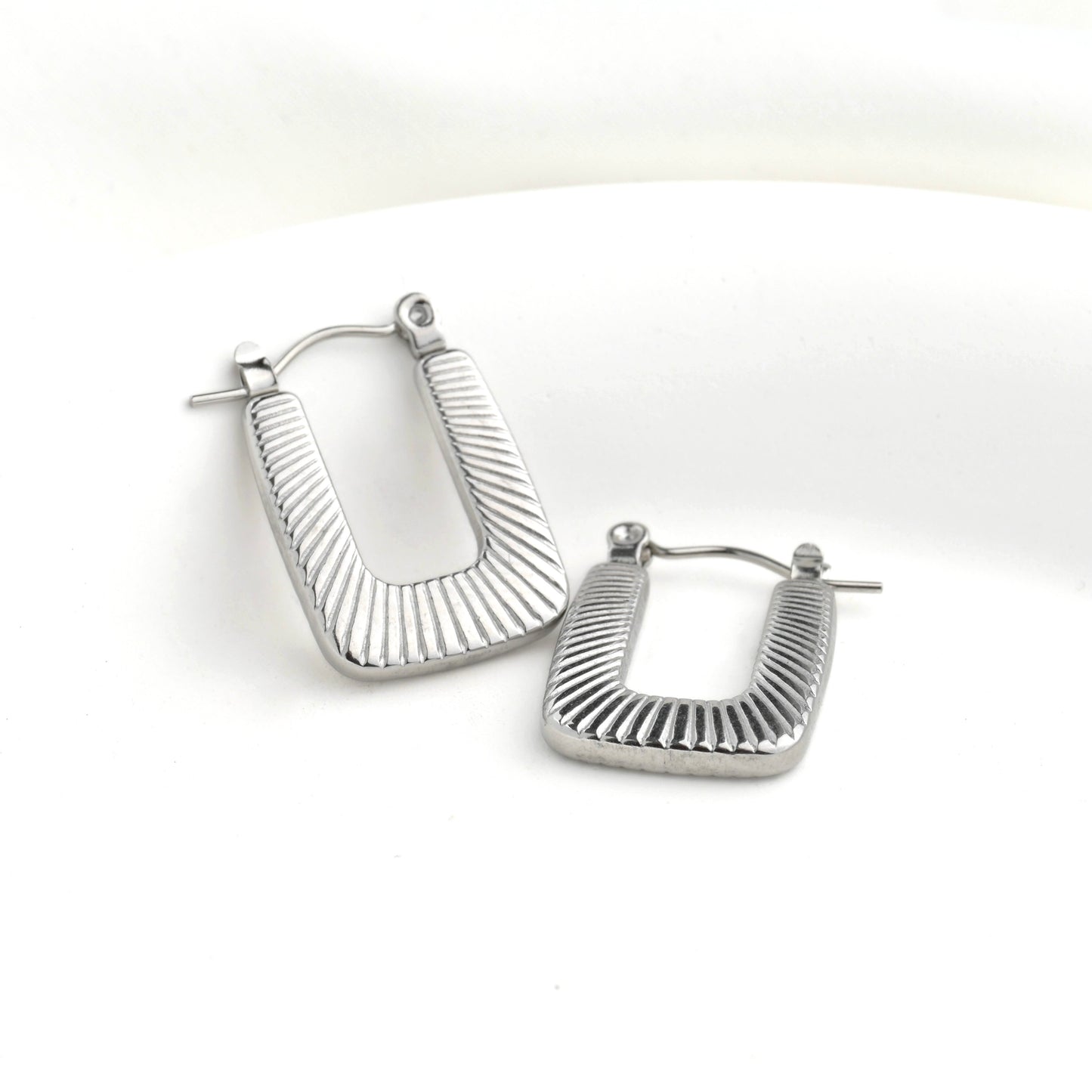 Pair of textured silver U-shaped hoop earrings on a white background