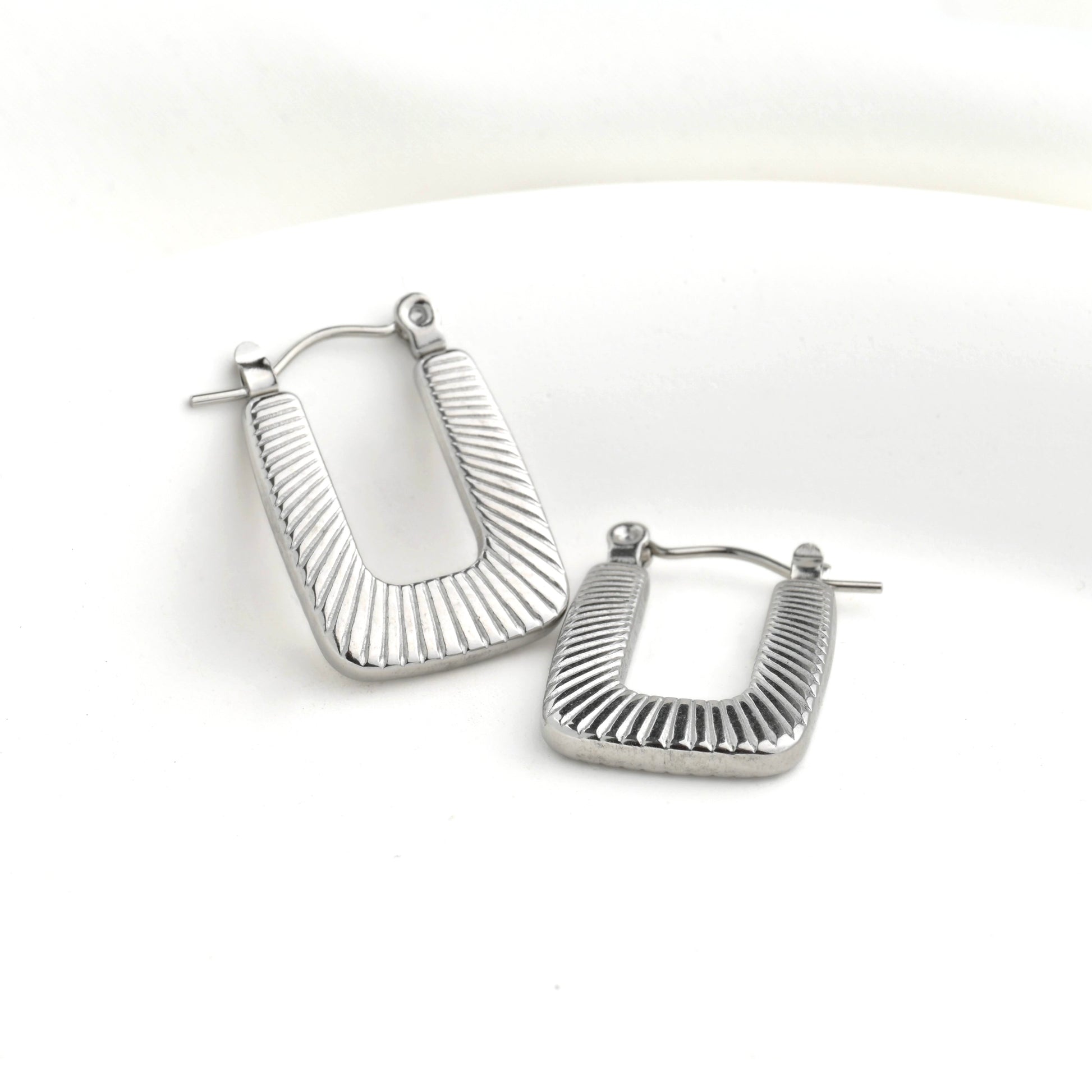 Pair of textured silver U-shaped hoop earrings on a white background