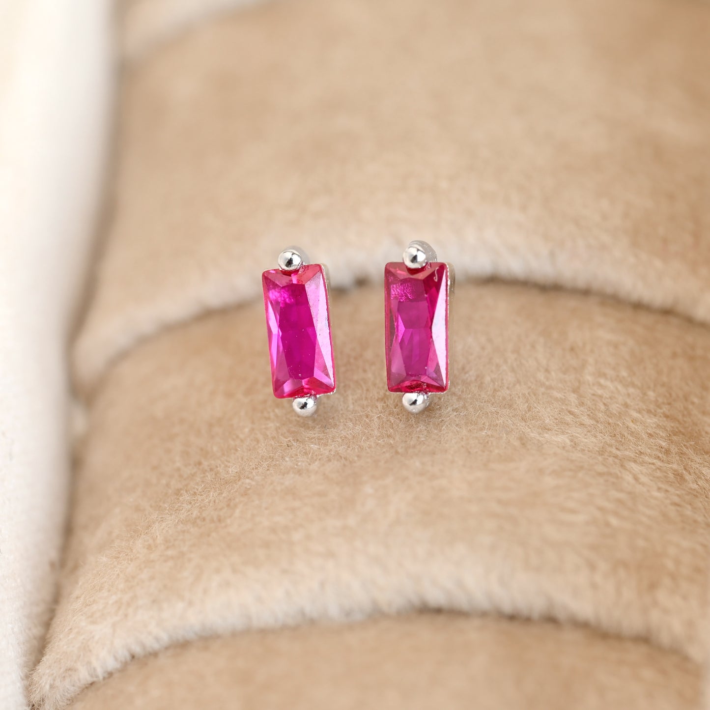 Pair of pin stud earrings on a beige surface