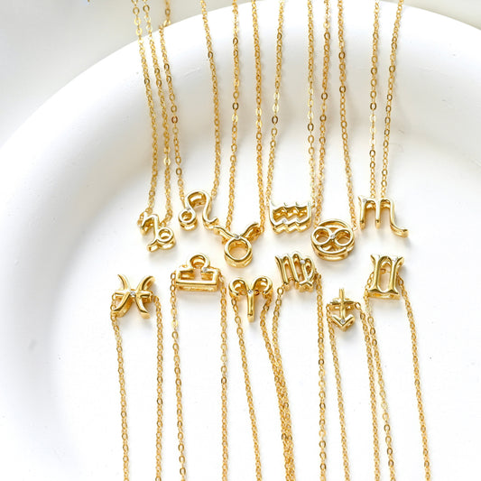 Twelve gold necklaces with zodiac symbol pendants in a white dish.
