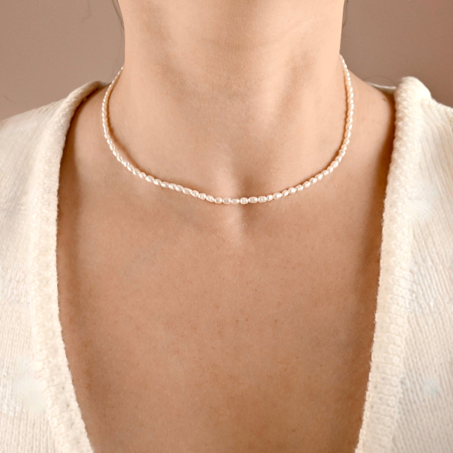 Delicate natural pearl necklace worn by a person with a neutral background