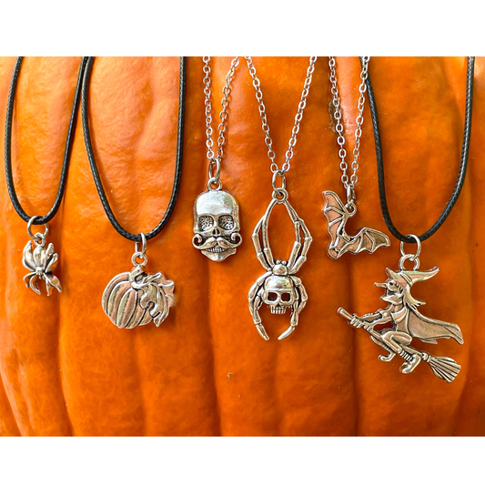 Halloween-themed necklaces with various pendants with black cord and silver chains on a pumpkin background