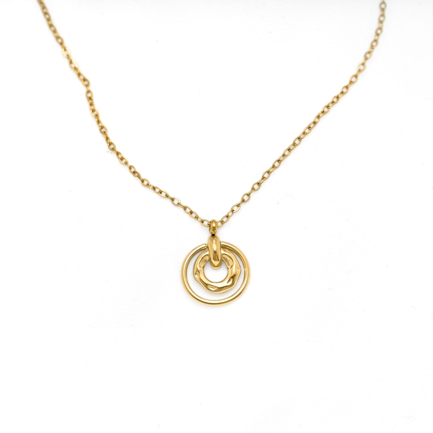 A delicate gold chain necklace featuring a double-ring pendant with one smooth ring and one textured, organic-shaped ring, displayed on a clean white background.