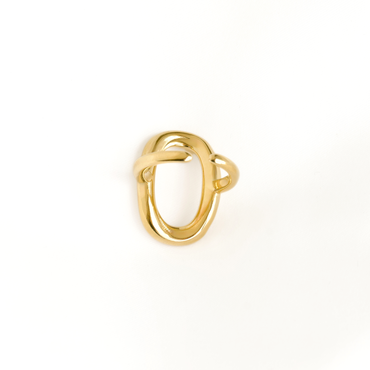 A polished gold ring with an abstract, intertwined loop design, photographed on a clean white background.