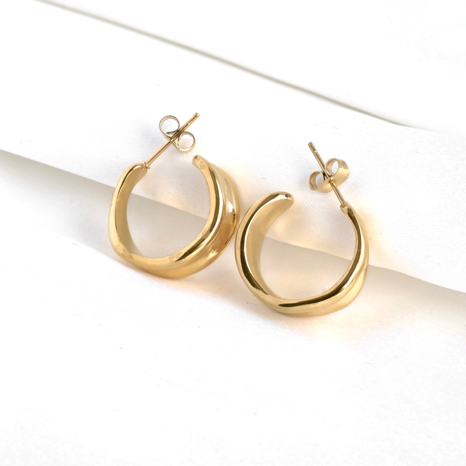 Gold C hoop earrings on a white background