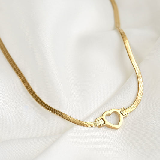 Gold flat snake chain necklace with a heart charm on a white background