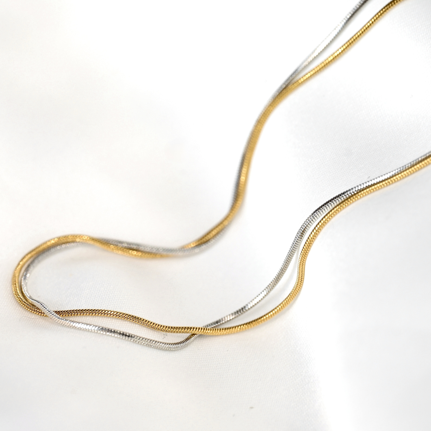 Mixed metal snake necklace on a white background