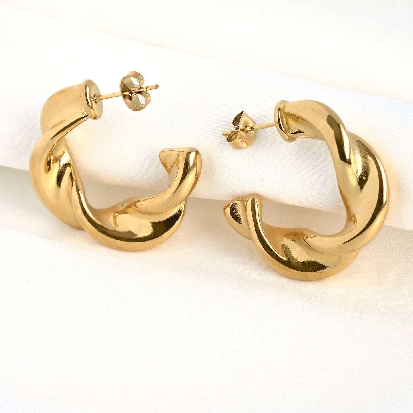 Medium gold croissant hoop earrings on a white background