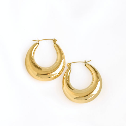 A pair of polished gold crescent-shaped hoop earrings on a clean white background.