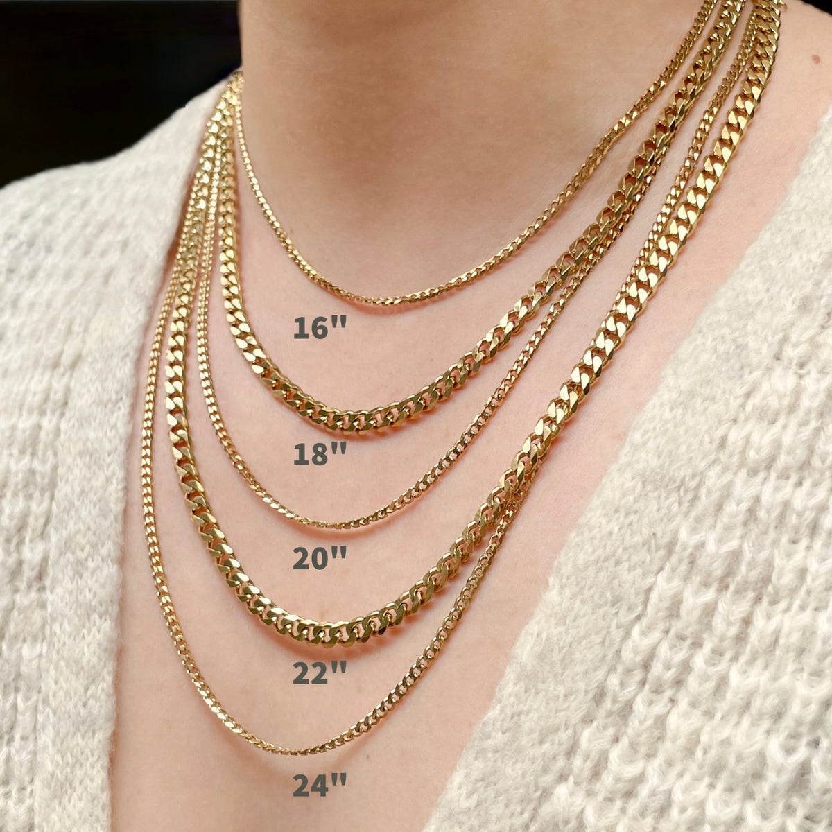 Close-up of a person's neck and upper chest wearing five layered gold-tone chain necklaces of different lengths, labeled 16 inches, 18 inches, 20 inches, 22 inches, and 24 inches.