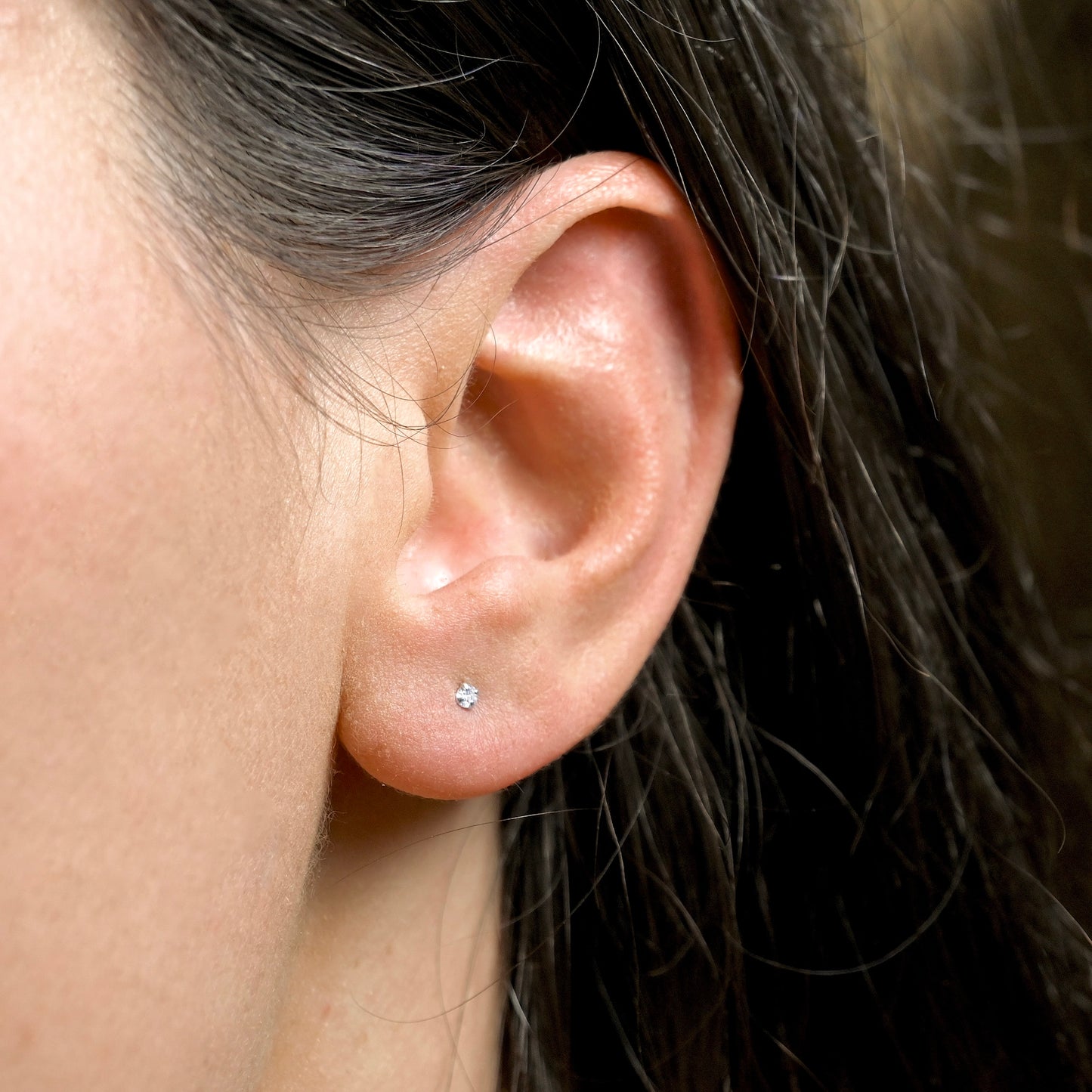 Close-up of an ear with a tiny diamond stud earring.