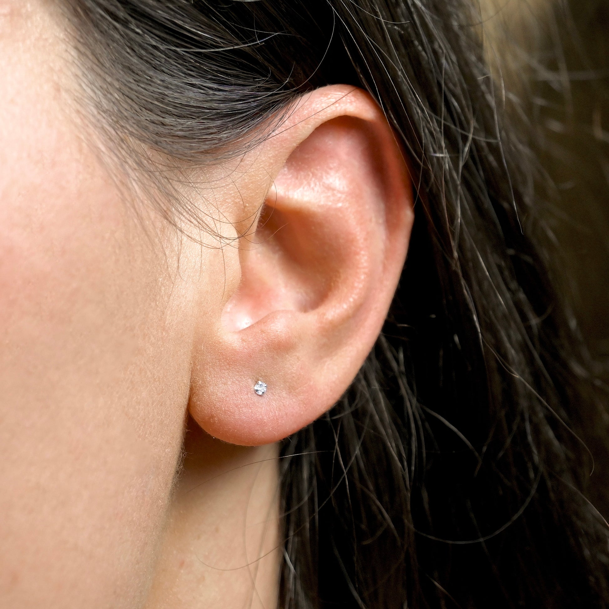Close-up of an ear with a tiny diamond stud earring.