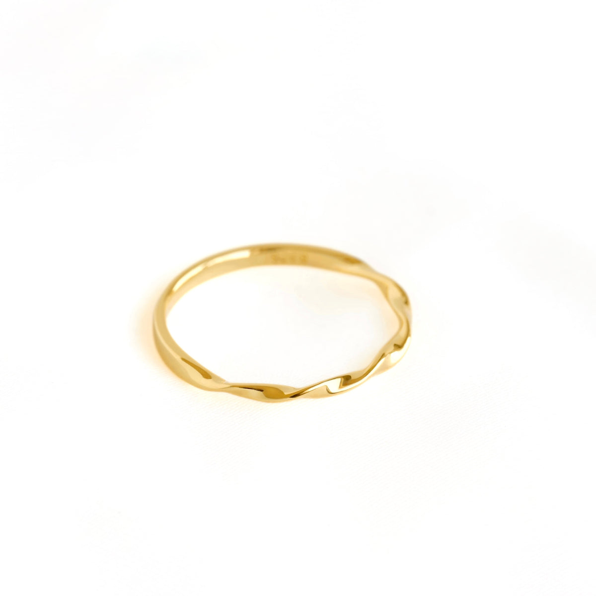 A thin gold ring with a textured, wavy, hammered finish, photographed on a clean white background.