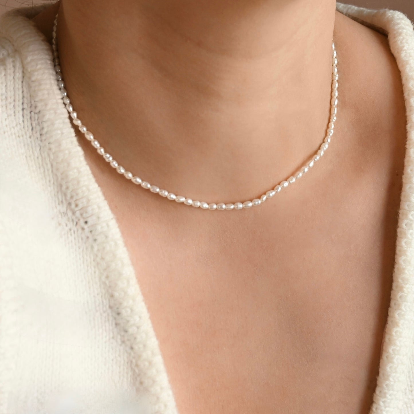 Pearl necklace worn by a person with a neutral background