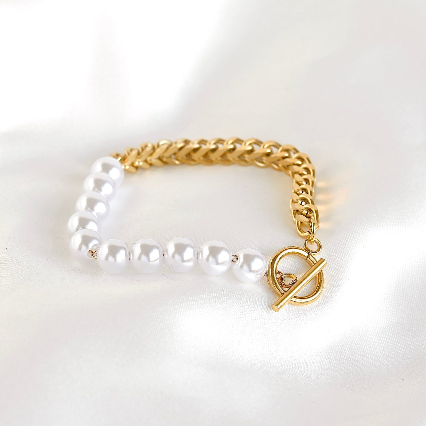 Bracelet with pearl beads and gold chain on a white background