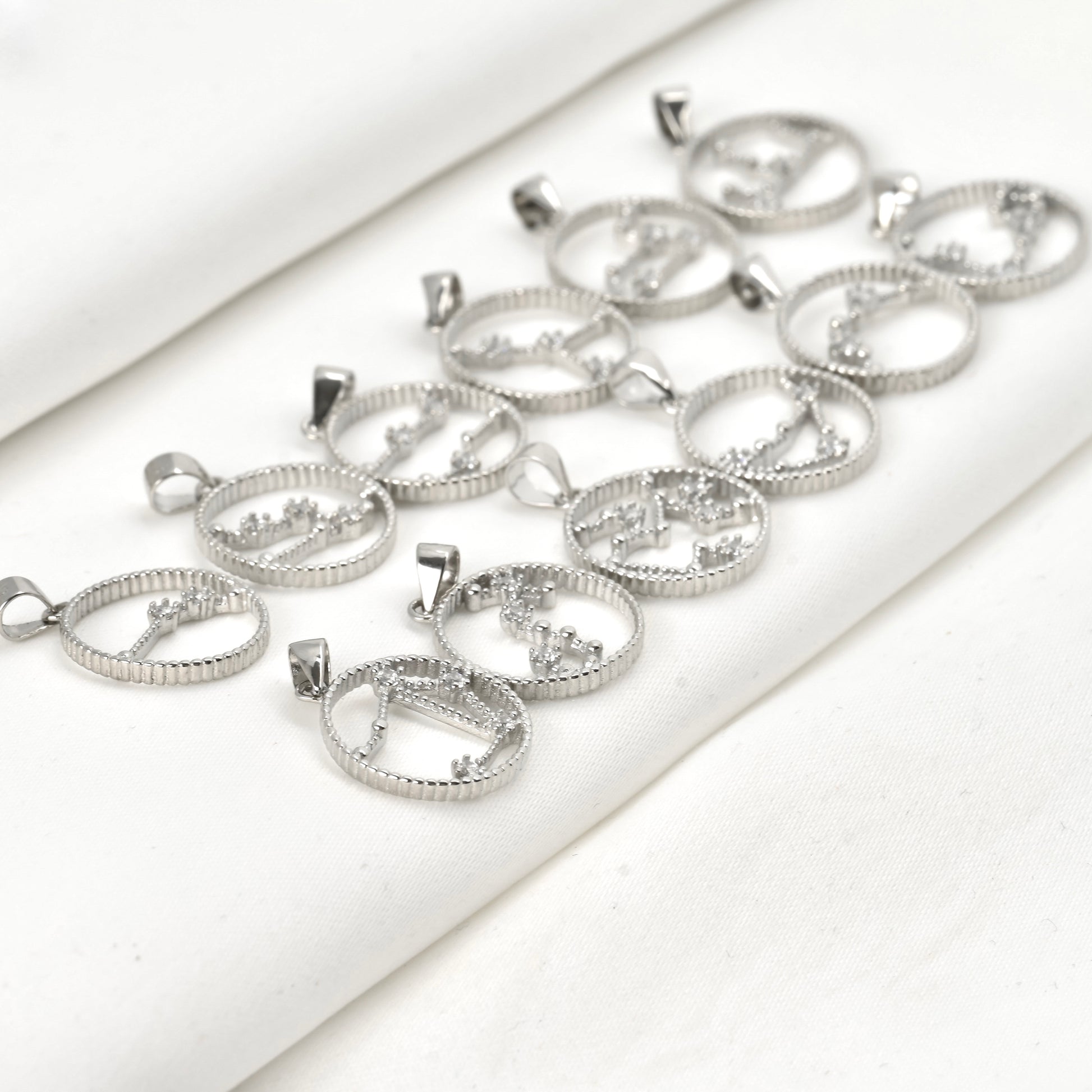 Round silver constellation pendants with CZ stones in place of stars on a white surface