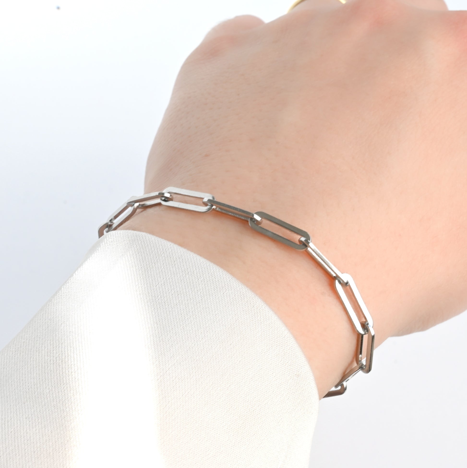 THick bold paperclip bracelet  in silver on a wrist with a plain background