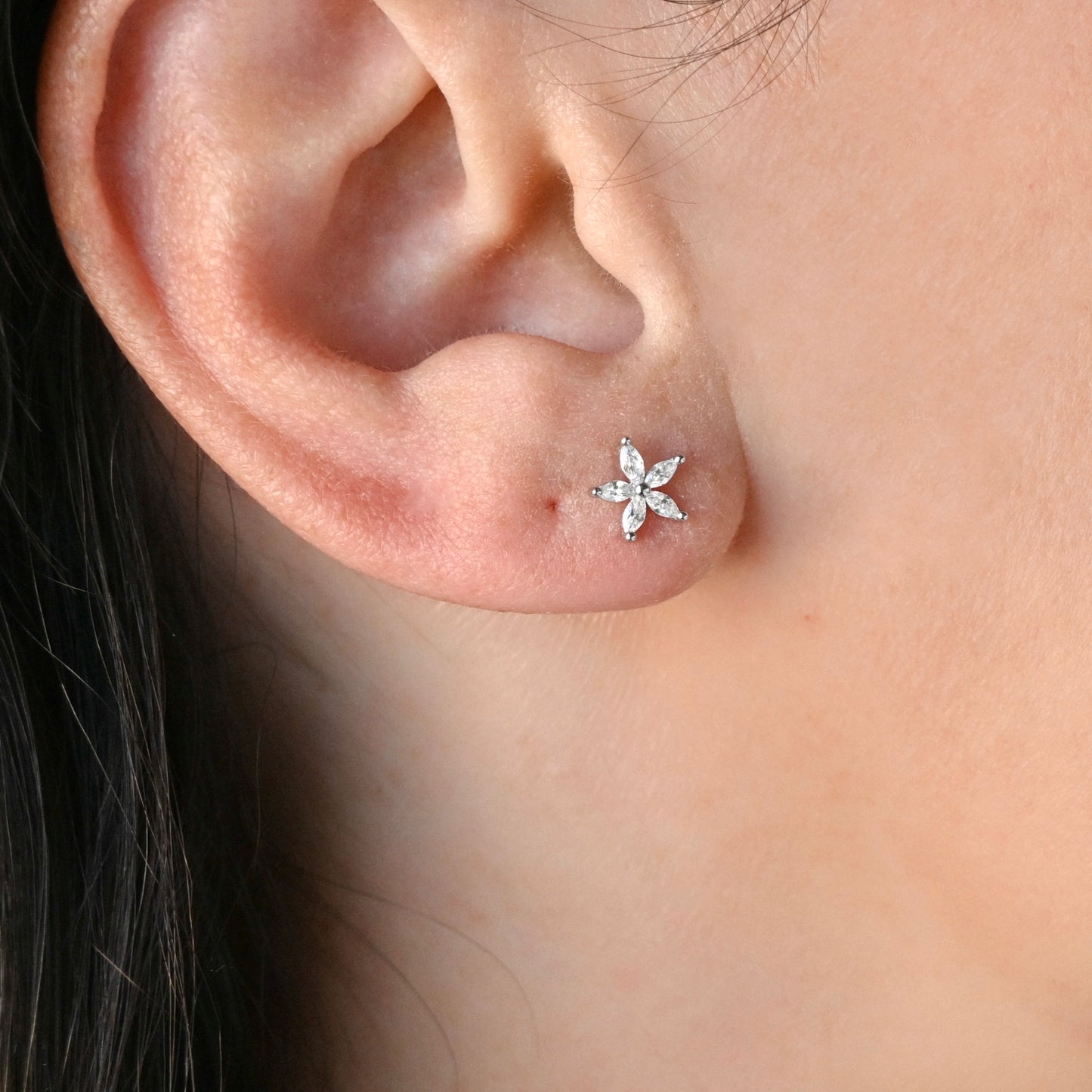 Close-up of an ear wearing a CZ flower earring.