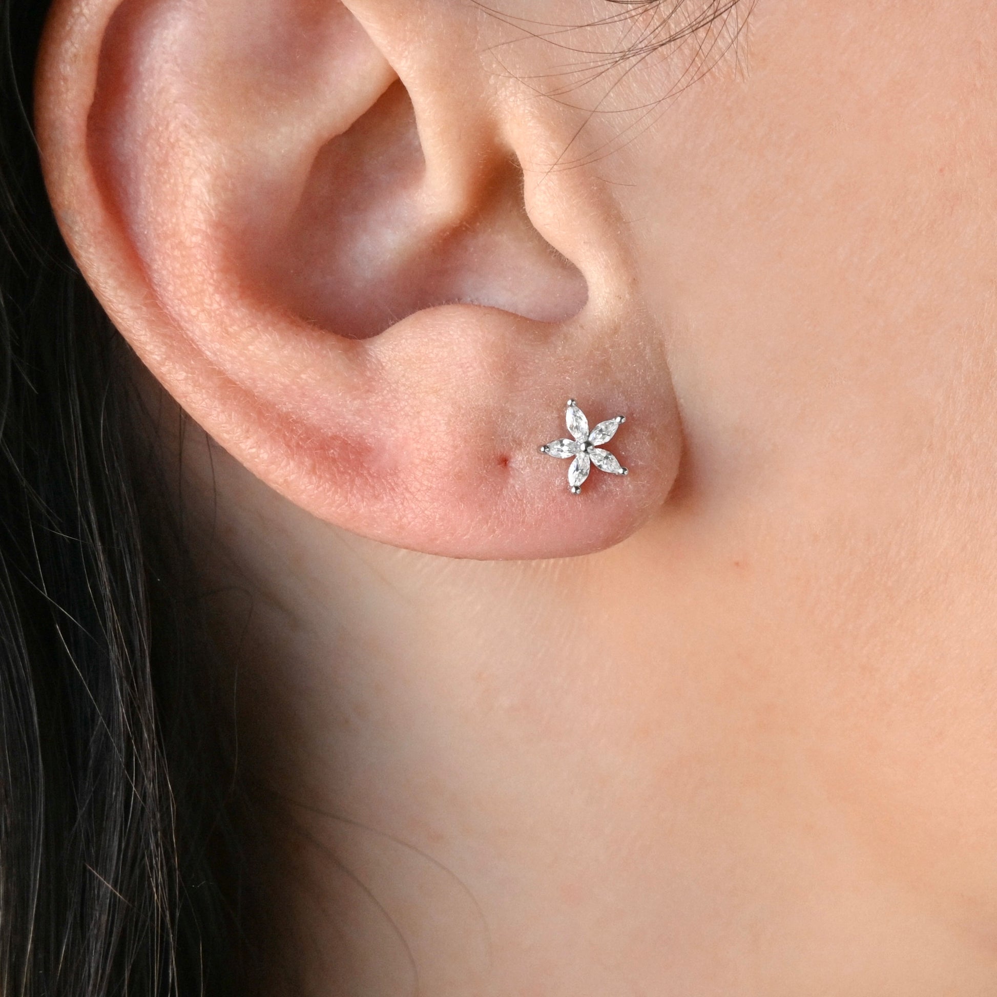 Close-up of an ear wearing a CZ flower earring.