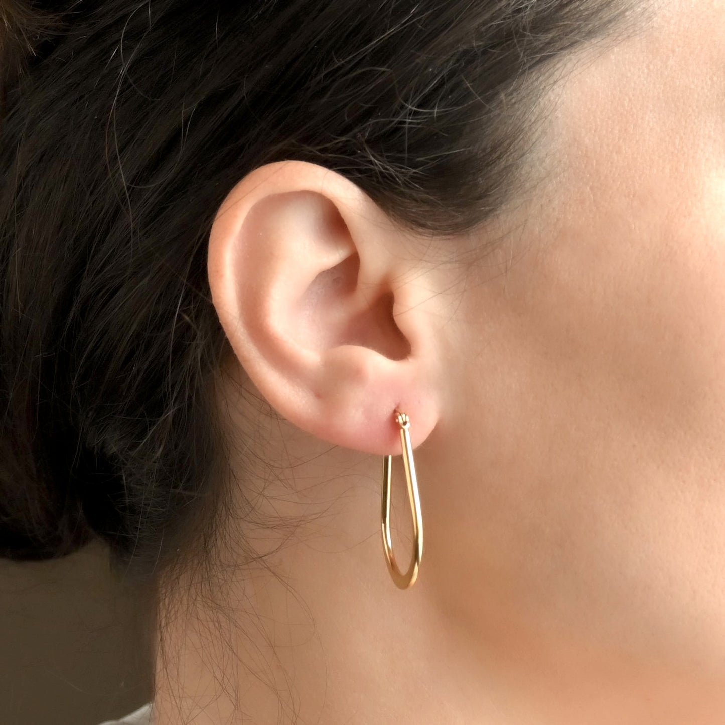 Side view of woman wearing gold teardrop earrings