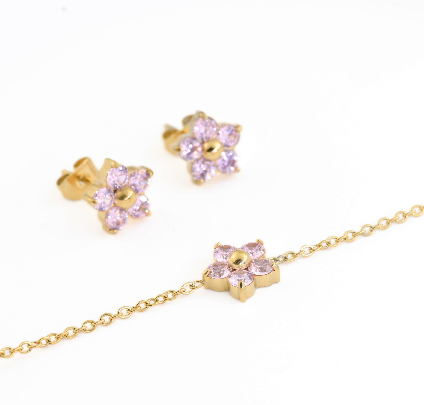 Gold jewelry set including a bracelet and two stud earrings with pink gemstone petals.