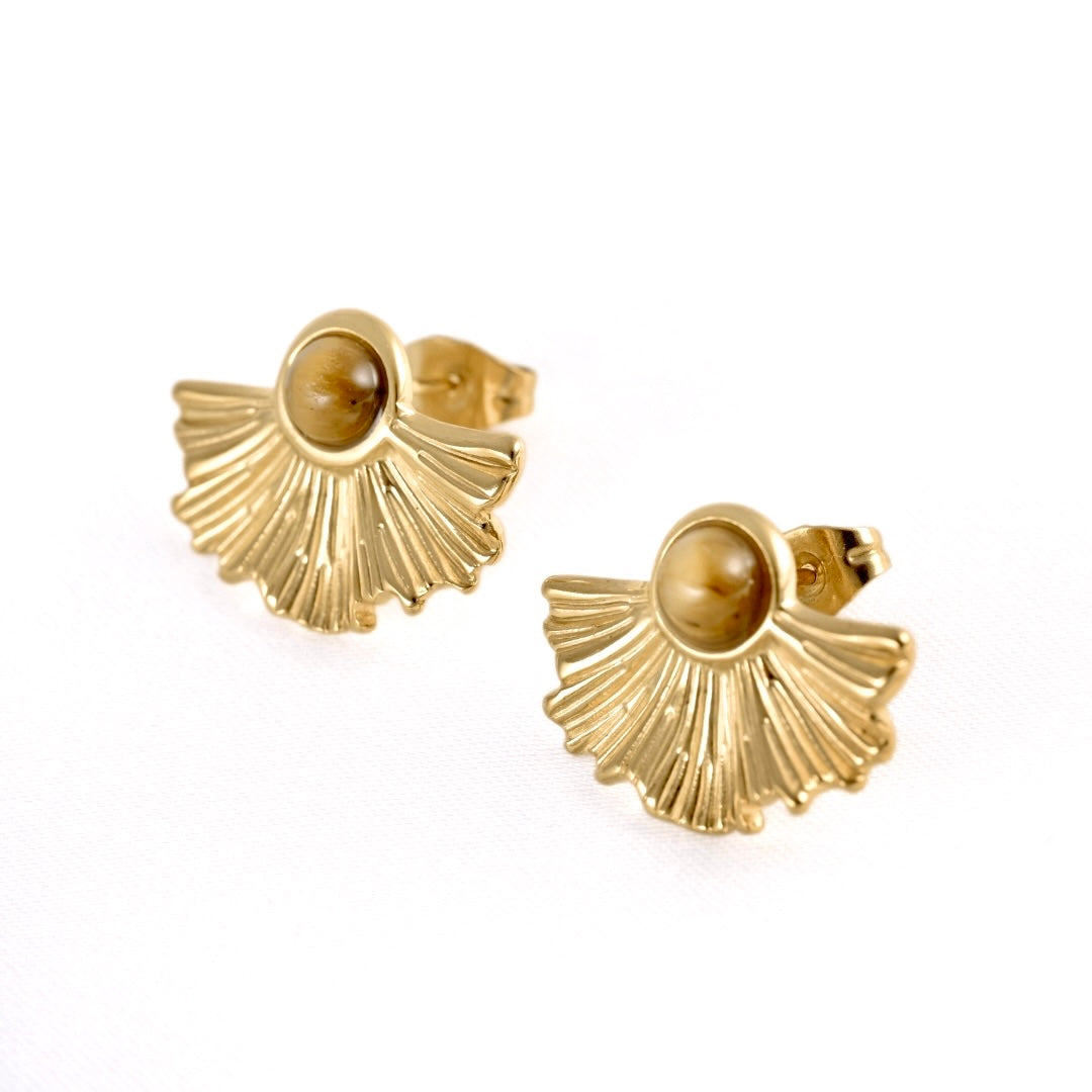 A pair of  textured gold fan-shaped stud earrings with a smooth, oval amber-brown center stone, displayed on a clean white background.