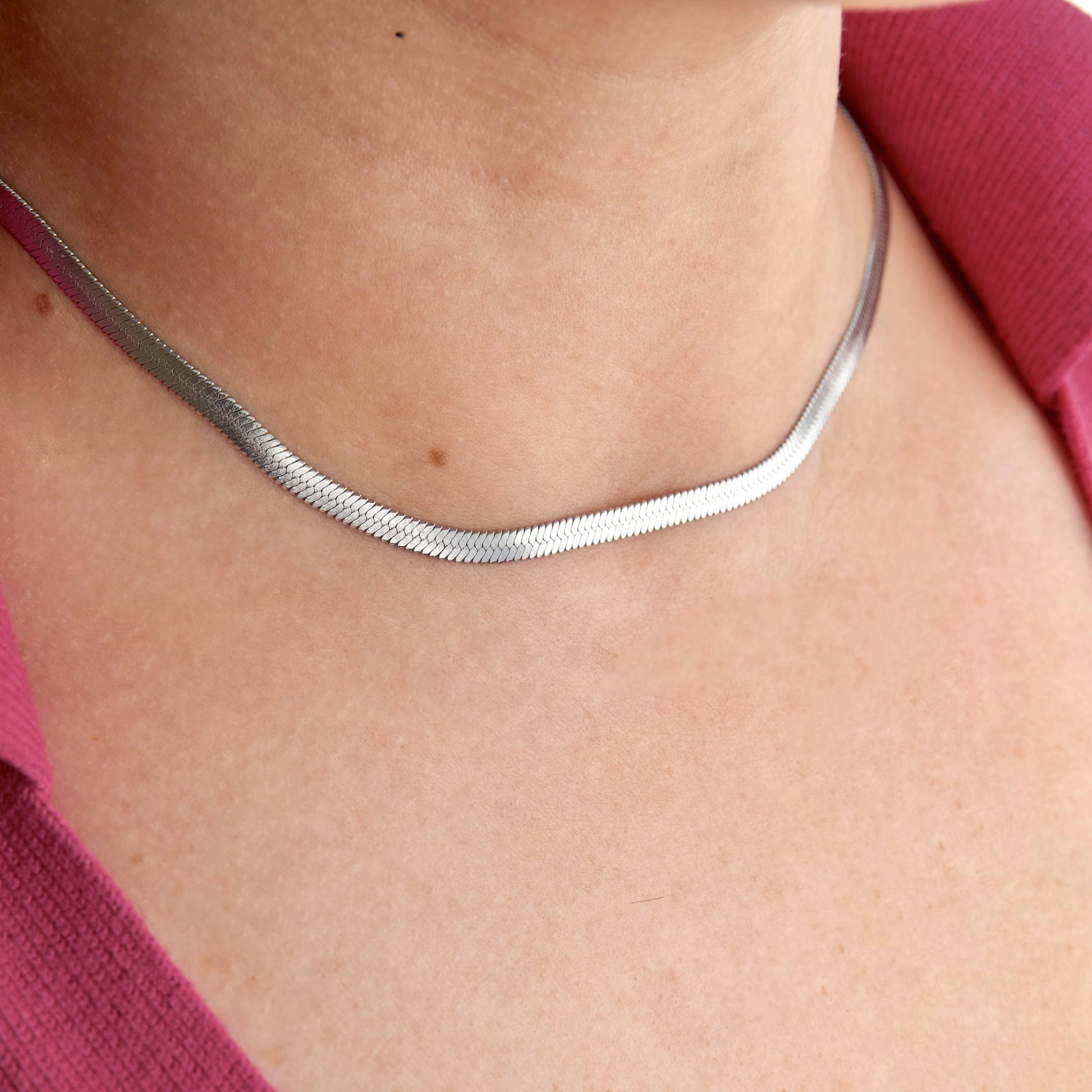 Silver  4mm herringbone choker necklace on a person wearing a pink top